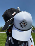 PINSEEKER Whiteout and Blackout Founders Squadron golf caps resting on a golf bag against blue sky
