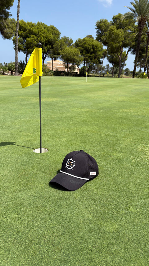 PINSEEKER Performance Golf Cap in Blackout on the green by the flag