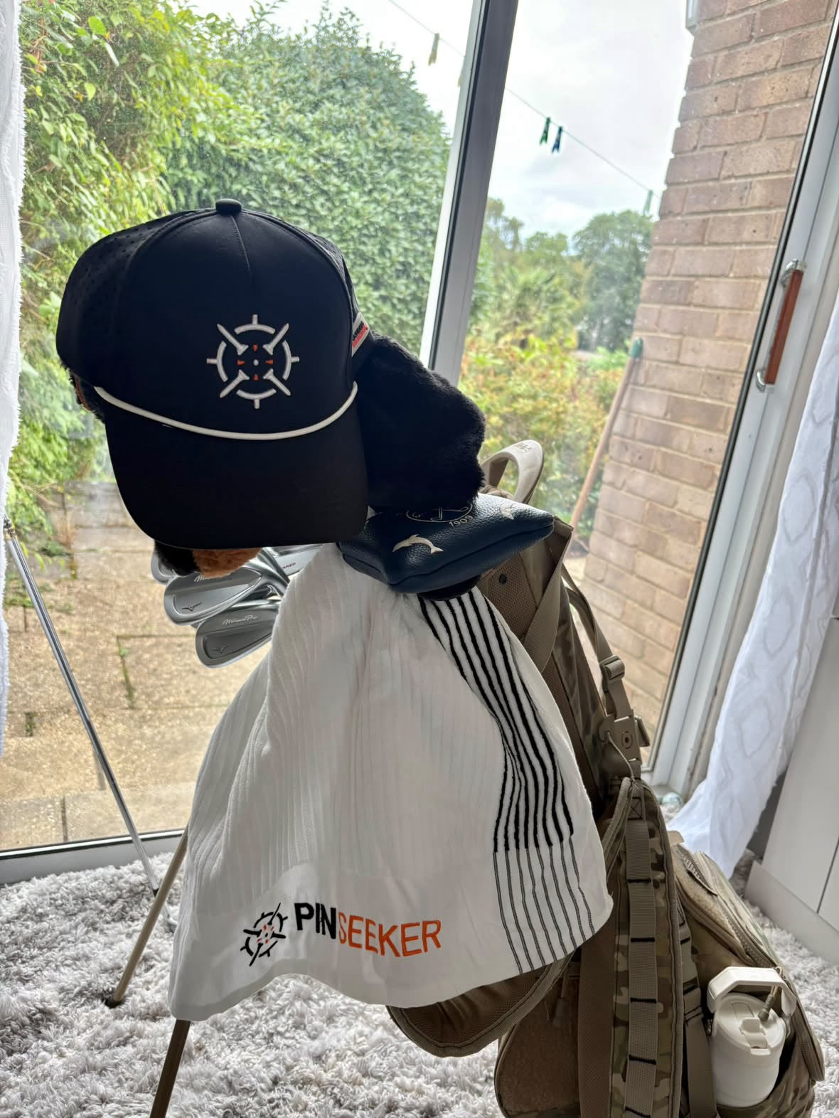 PINSEEKER Performance Golf Cap in Blackout with a Whiteout golf towel on a golf bag
