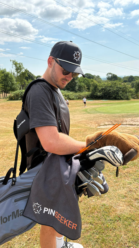 Golfer on the course in the Blackout cap, towel on the bag