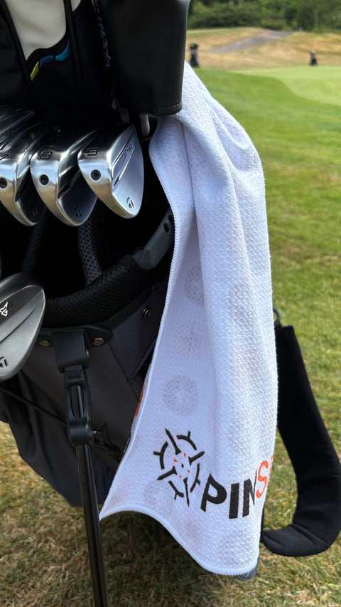 PINSEEKER Tour Golf Towel in Whiteout on a stand bag on the course